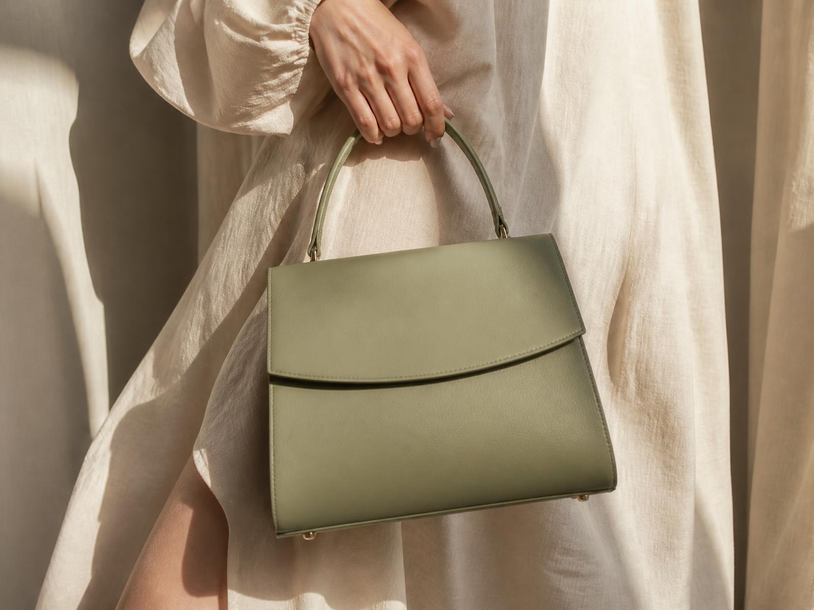Sac à main en cuir vert sauge tenu à la main
